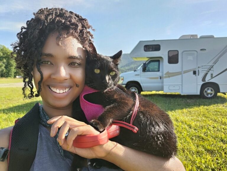 a woman and her cat with an RV behind