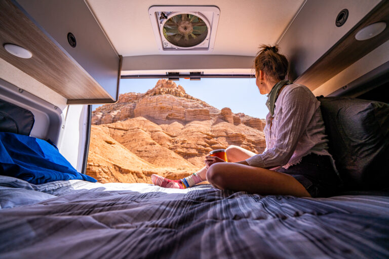 a woman in a campervan looking at red rocks out the window