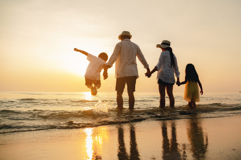 a family walking along a beach at sunset