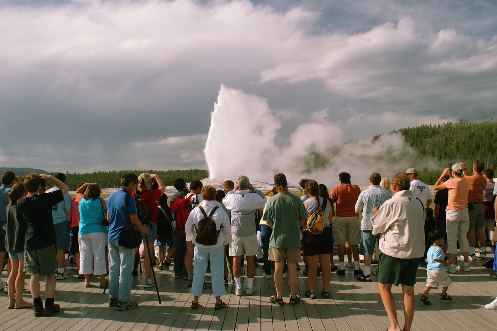 a crowd of people around Old Faithful geyser