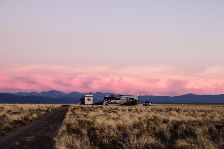 an RV parked in front of mountains at sunset