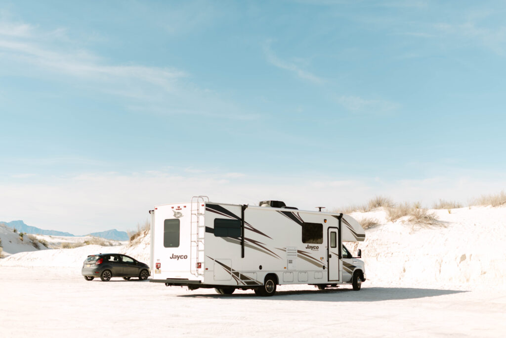 A class C camper parked in a sandy desert