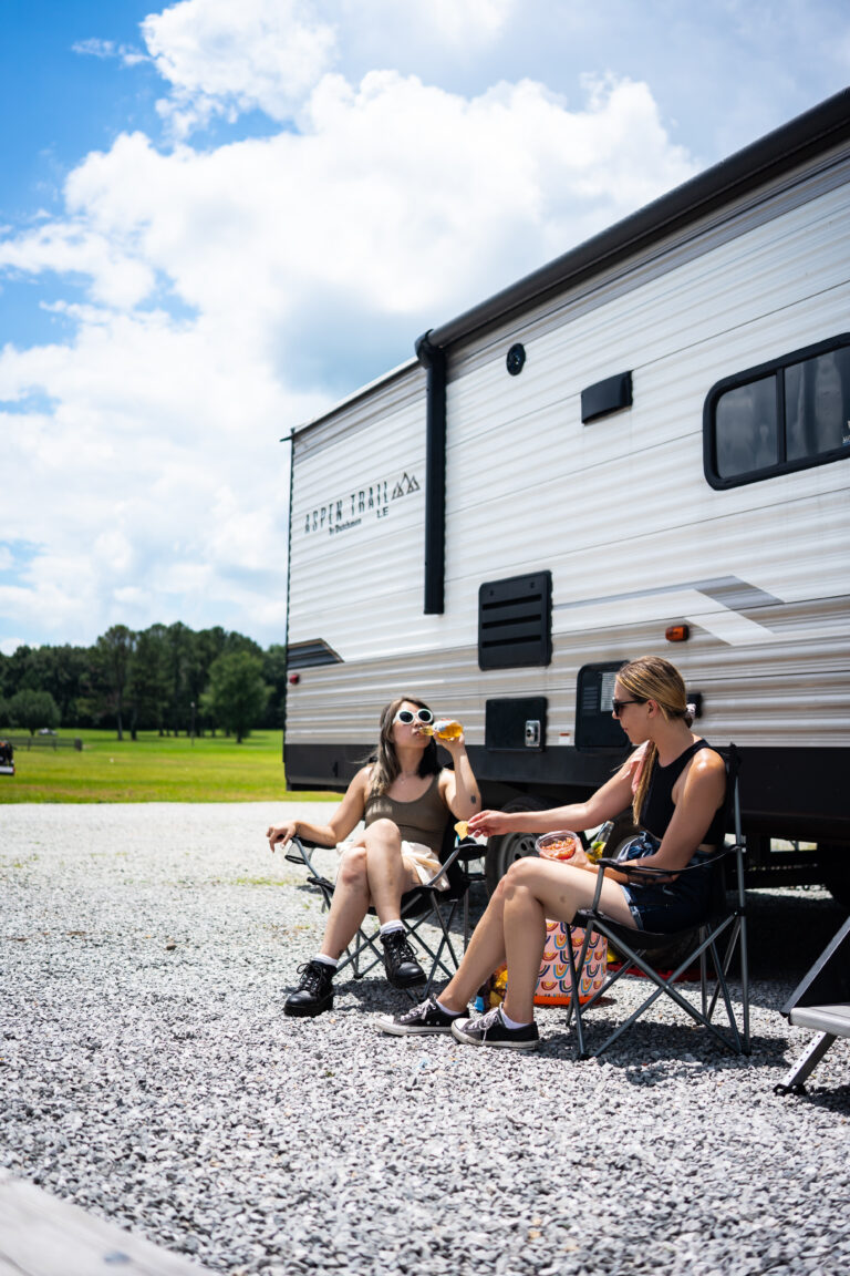 two women relaxing in front of an RV