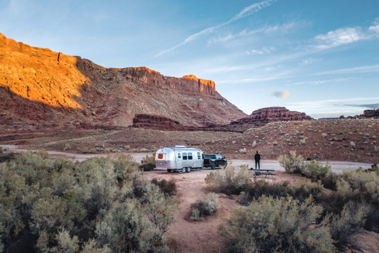 an Airstream set up near rocks in the desert