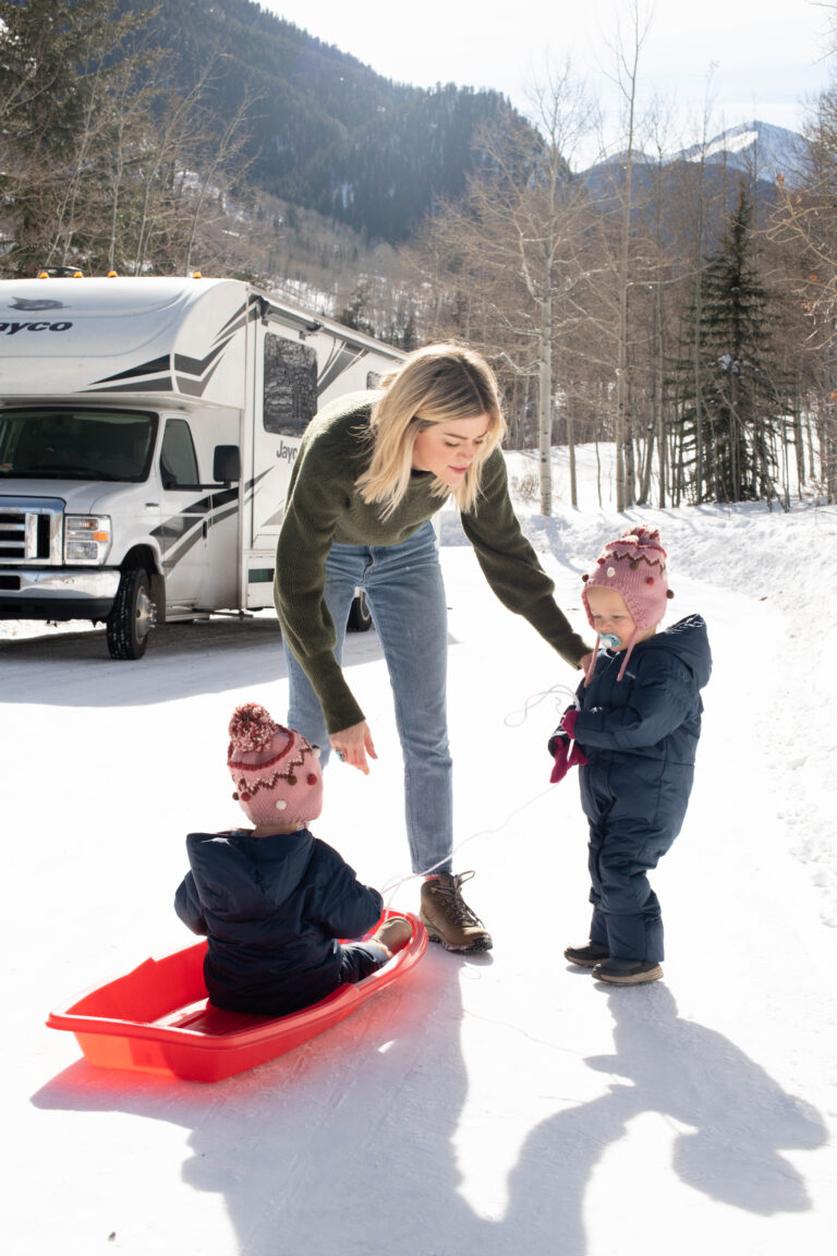 mom and kids in front of an RV in the snow