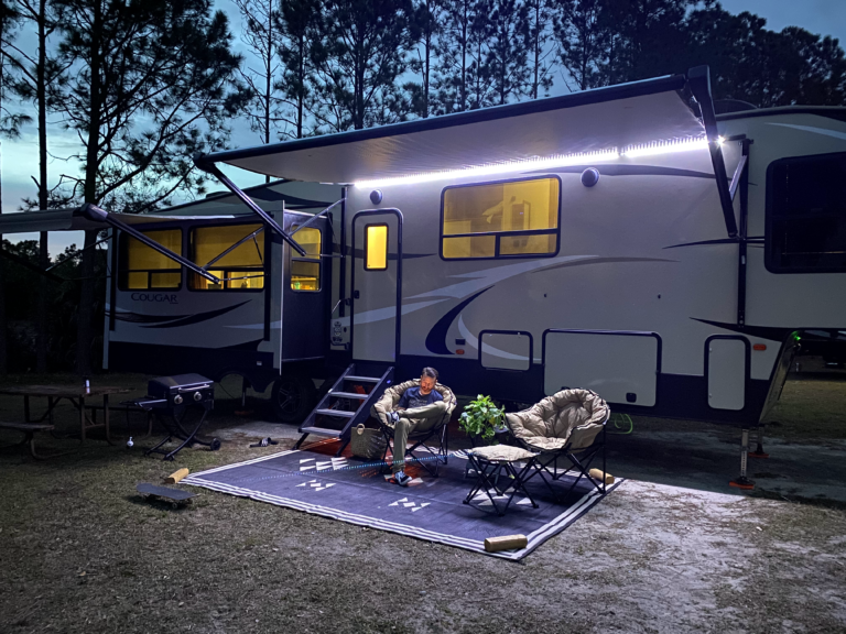 a man relaxing in front of an RV