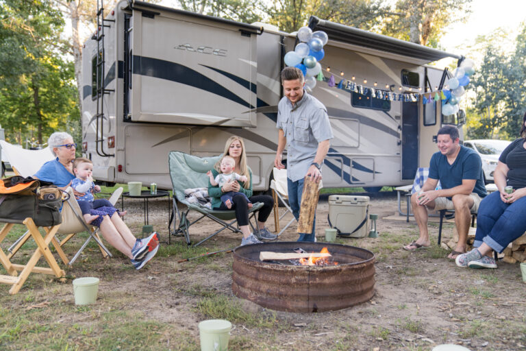 a man building a campfire in front of an RV