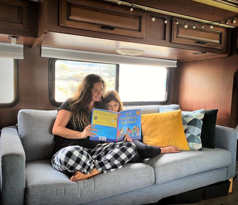 a woman reading a book to a child on an RV couch