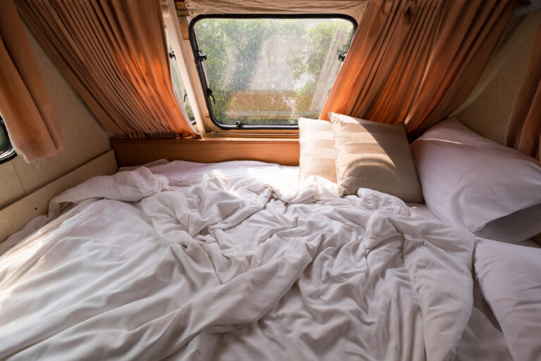 an RV bed piled with blankets