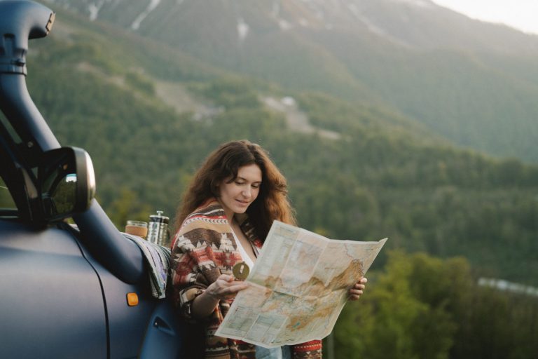 Woman looks at roadmap while leaning on the outside of her RV