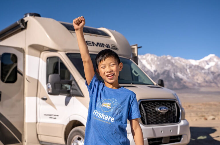 a kid in front of an RV by the mountains