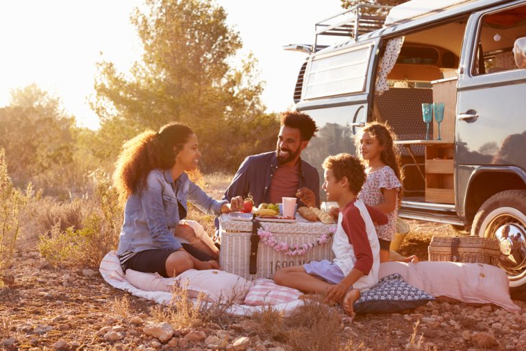 family enjoying a picnic outside an RV