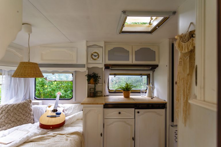 Inside a small RV - guitar rests on a bed next to a small kitchenette