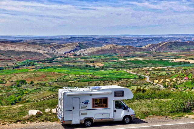 an RV driving past a green meadow with hills beyond