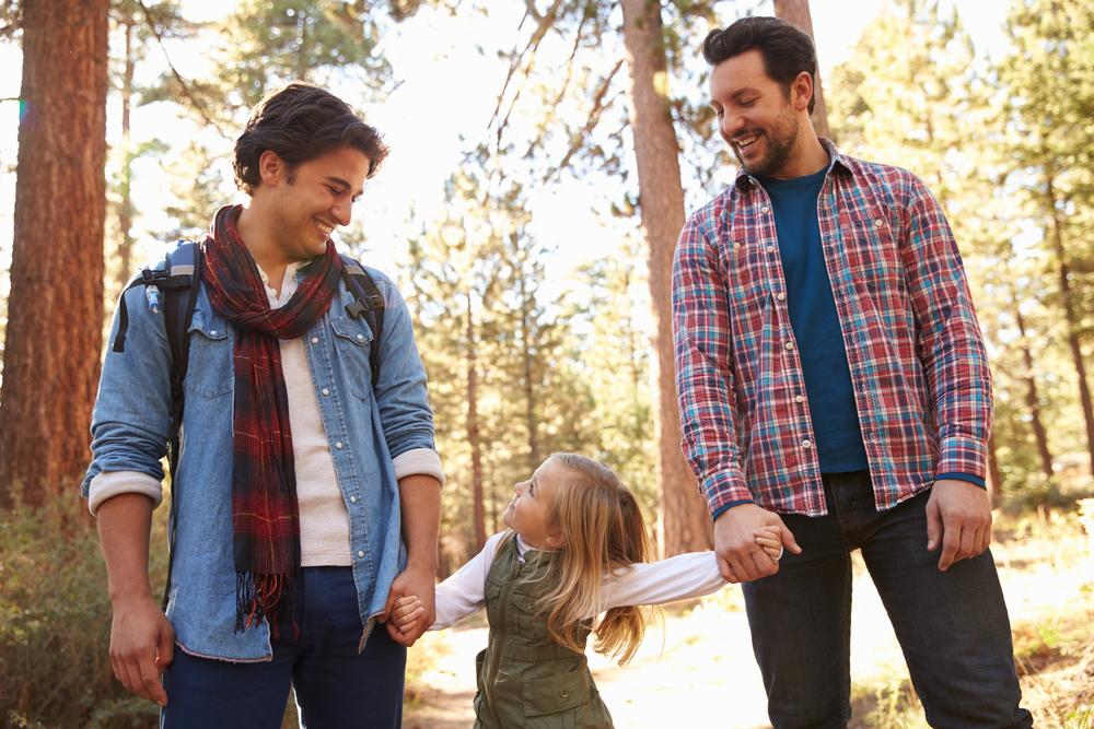 Male Couple With Daughter Walking Through Fall Woodland