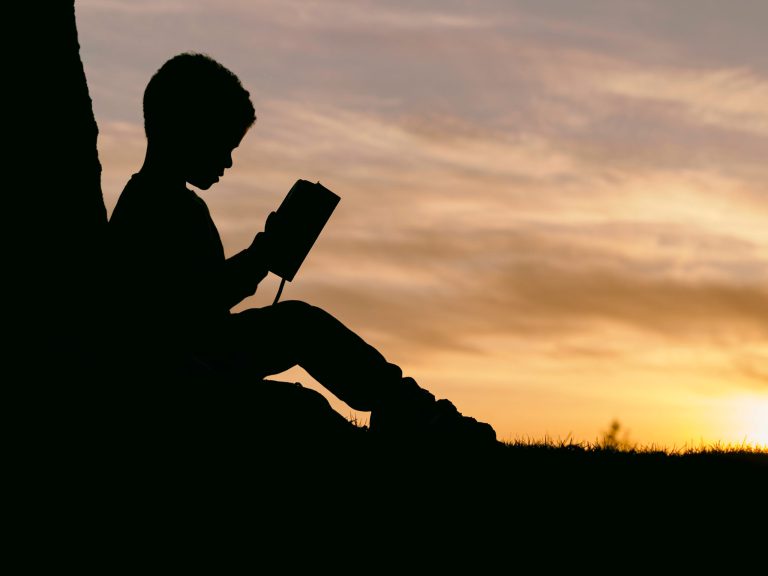 a silhouette of a boy reading