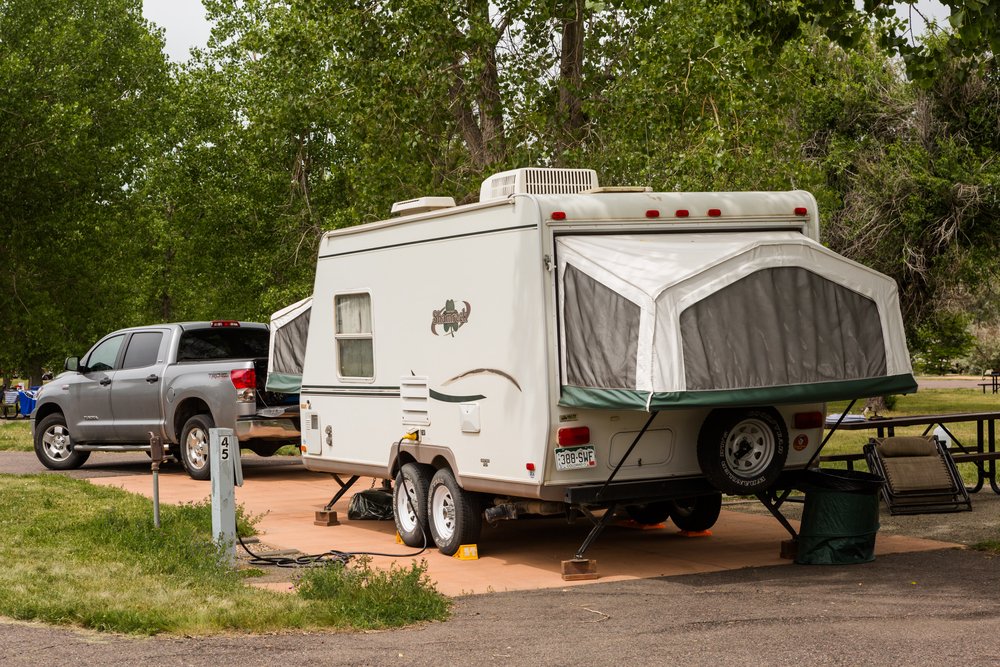hybrid RV hitched to pick up truck parked at campsite