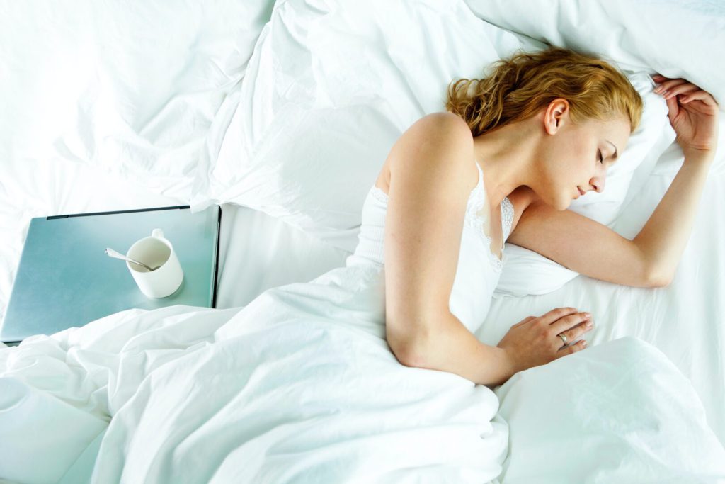 woman resting in bed with a cup of coffee