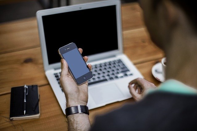 a man on a cell phone while working at a computer