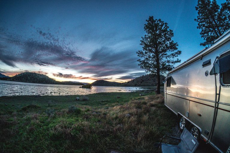 an Airstream trailer at sunset next to a lake