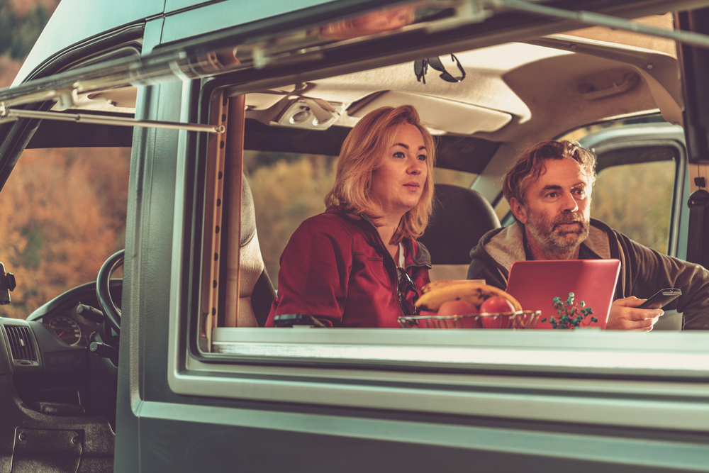 Couple Watching Exciting TV Game Inside Self Made Camper Van RV During Scenic Autumn Weekend Getaway.