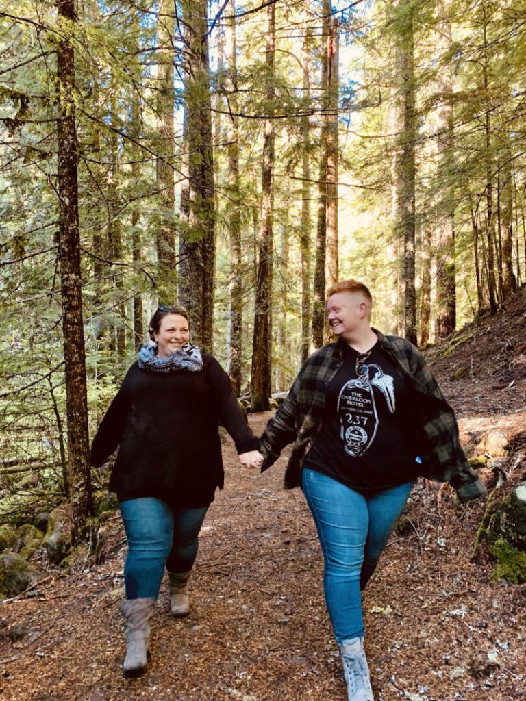 Women hold hands and walk in forest