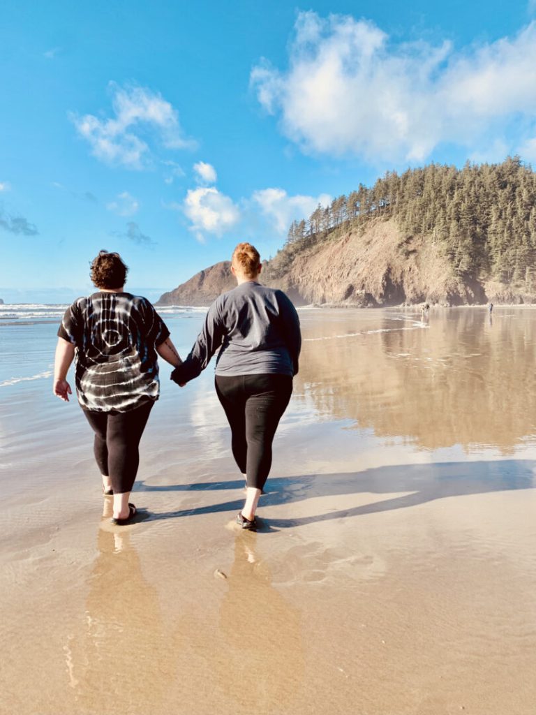 Women hold hands and walk along beach