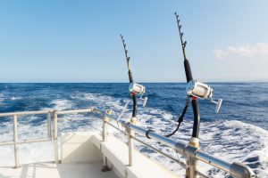 two fishing poles secured to rails on a boat sailing through open ocean waters.