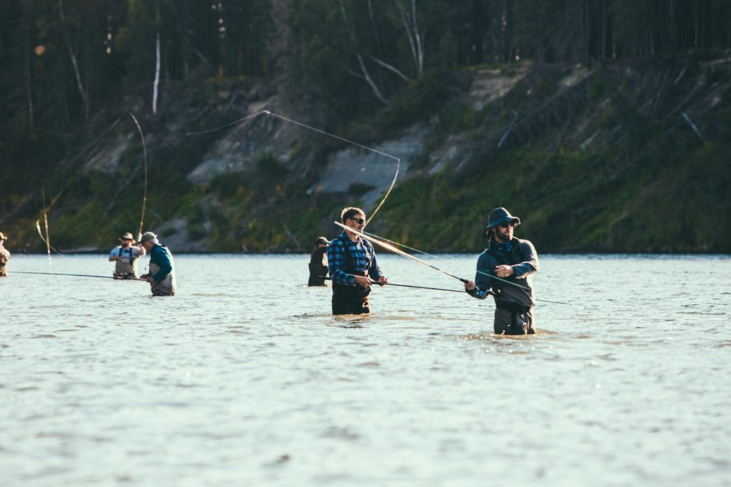 A group of men wading in a river and fly-fishing. 