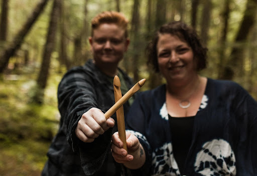 Couple extends their arms out, each holding a crochet hook