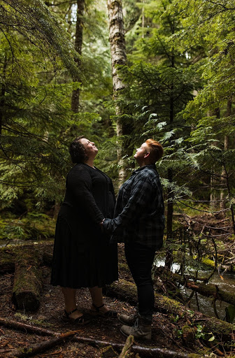 Couple holds hands and looks upward in the middle of the woods