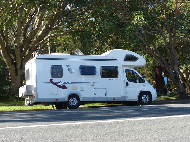 A Class C camper set up under shady trees