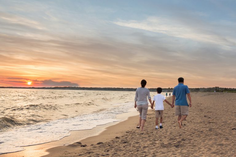 a family enjoying a stroll on the beach at sunset