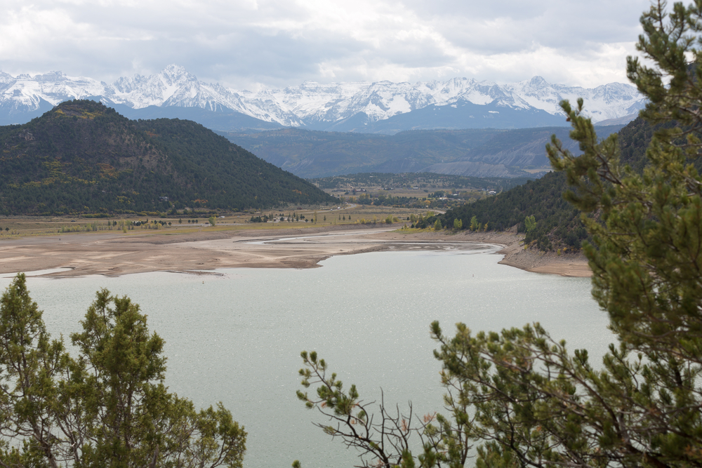 Ridgeway Reservoir and The Sneffels Range in a bright day light misty cloudy sky as seen from Ridgway State Park near Ridgway, Colorado, USA.