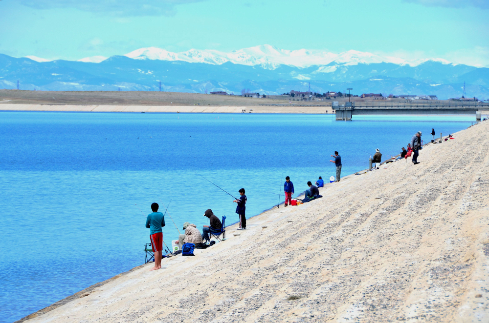 Aurora, Co, USA. March 9, 2007. Unidentified people fishing at the Aurora Reservoir in Aurora Colorado on a warm weekend with the Rocky Mountains in the background.