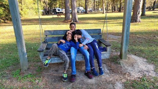 Three brothers sit together on a bench swing