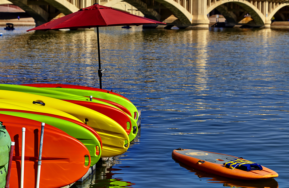 Kayak rentals stacked on dock with umbrella near bridge at Tempe Beach Park