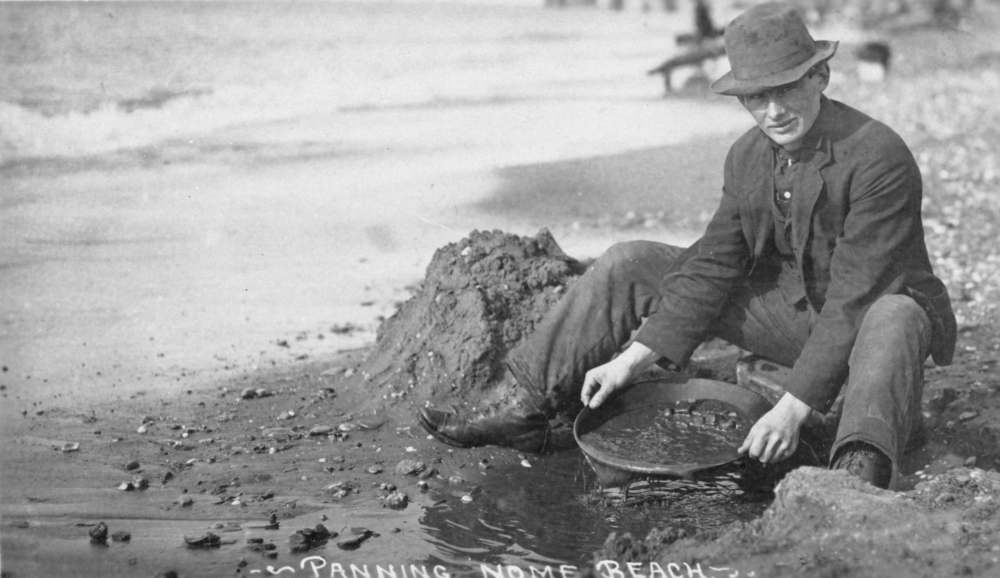 Man panning gold on Nome, Alaska beach in the early 20th century.