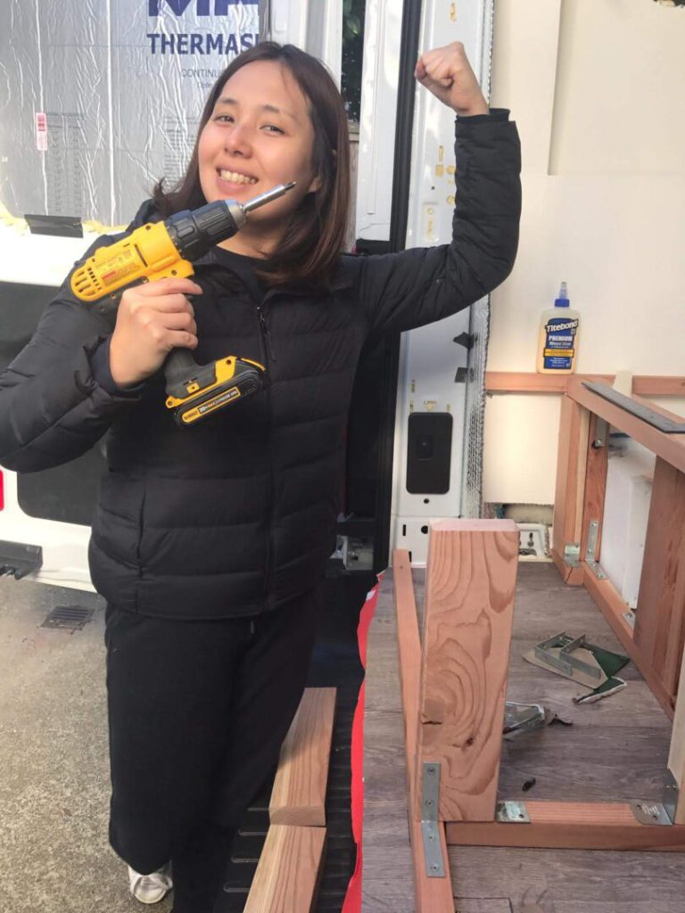 Woman holds drill while working on her campervan
