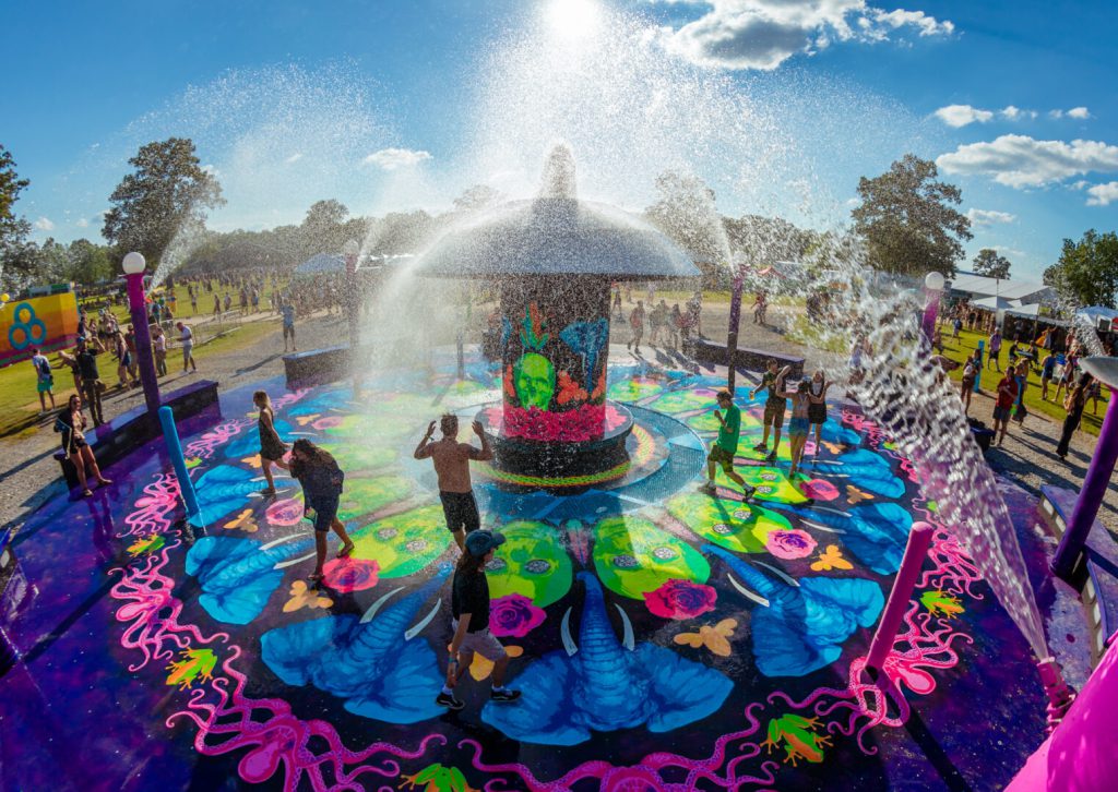 People gather at colorful mushroom fountain at bonnaroo