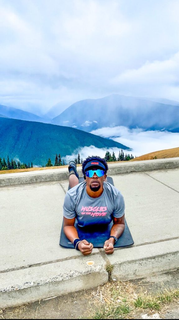 Man stretches on yoga mat near a mountain landscape