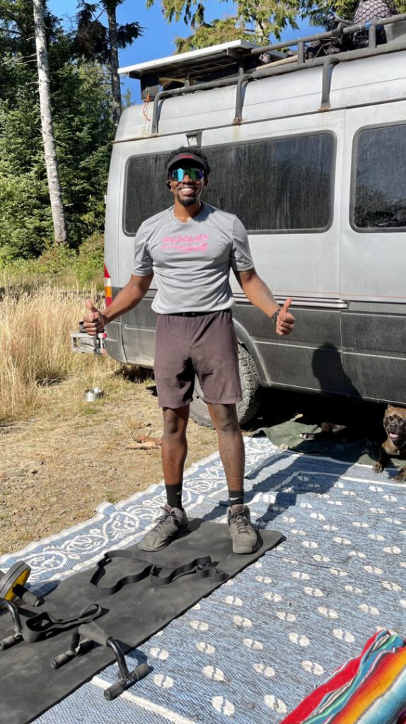 Man smiles as he exercises in front of his campervan