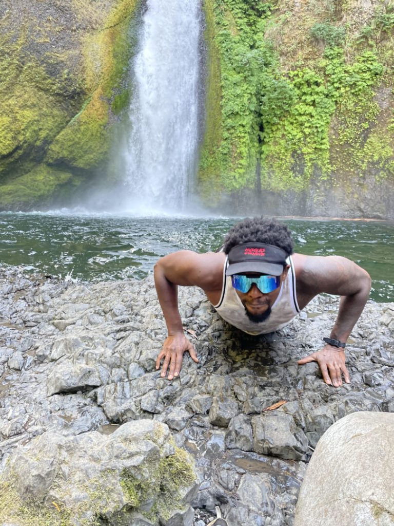 Man does a push-up in front of a waterfall