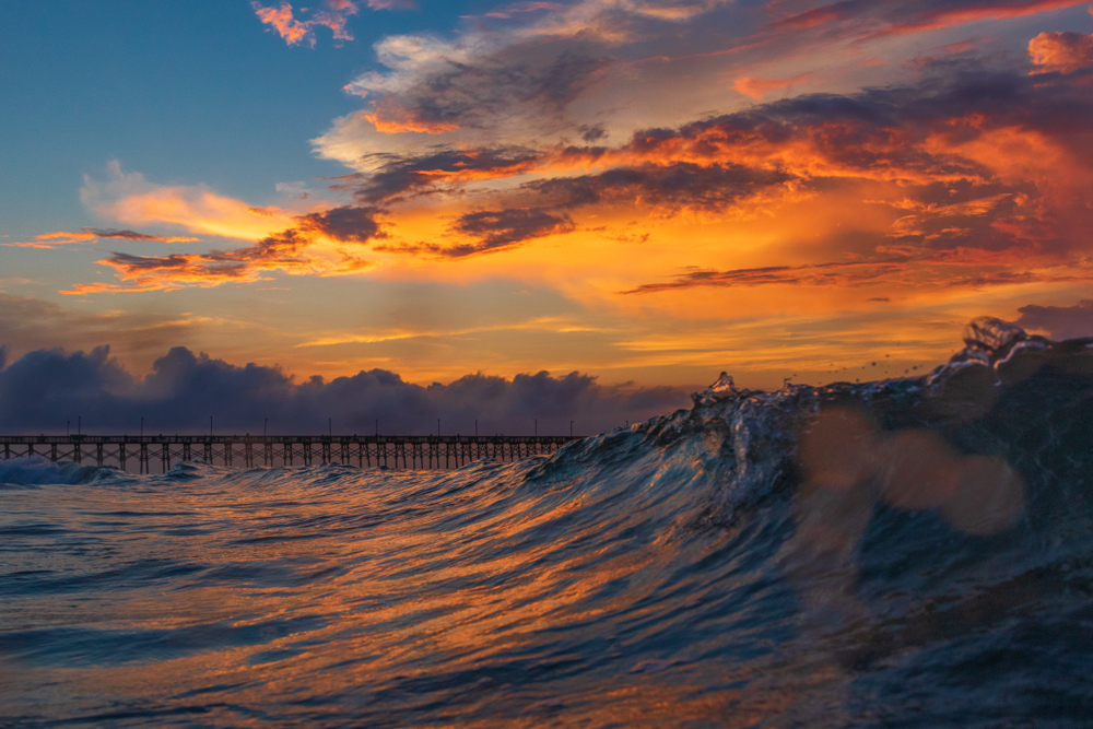 Sunrise or sunset with gorgeous orange sky and a pier in the distance.