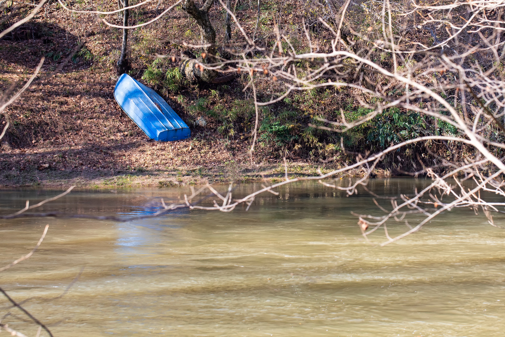 Small blue metal boat rests upside down on the western bank of the Yadkin River in Wilkes Couny, North Carolina.