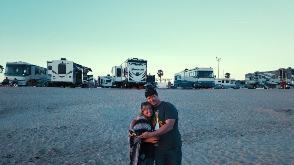Couple on the beach standing in front of RVs