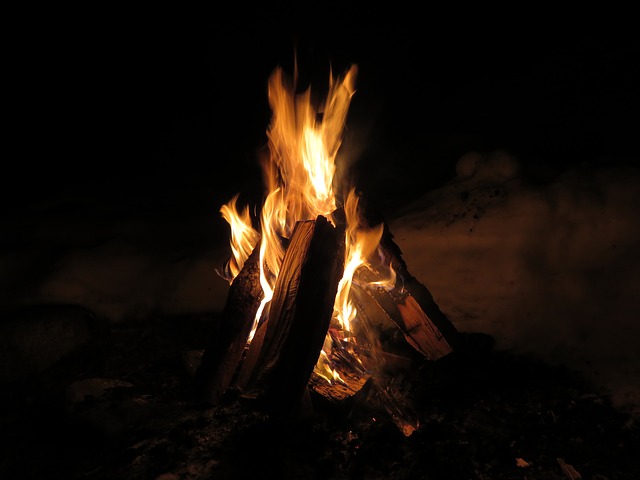 a teepee style campfire burns against a dark night