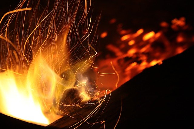 a campfire burning with sparks flying around the fire