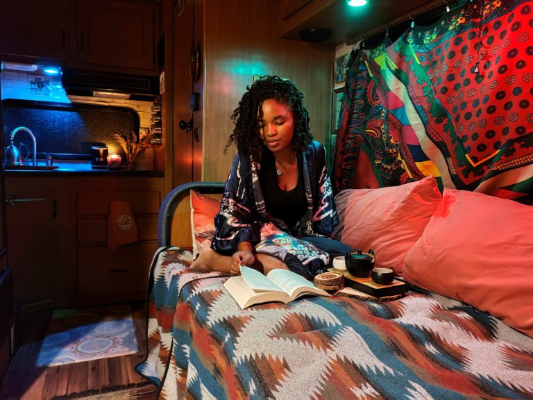 Bedroom of Class C RV lit with colored lights