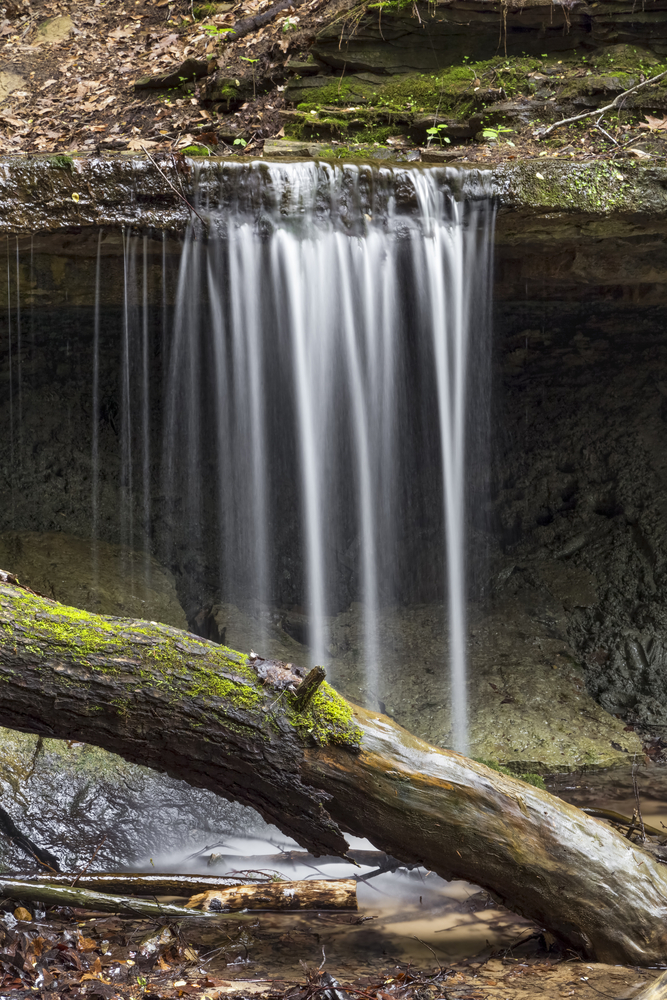 Maidenhair Falls, a small waterfall in Indiana's Shades State Park, plunges over a rock ledge with a recess cave behind.